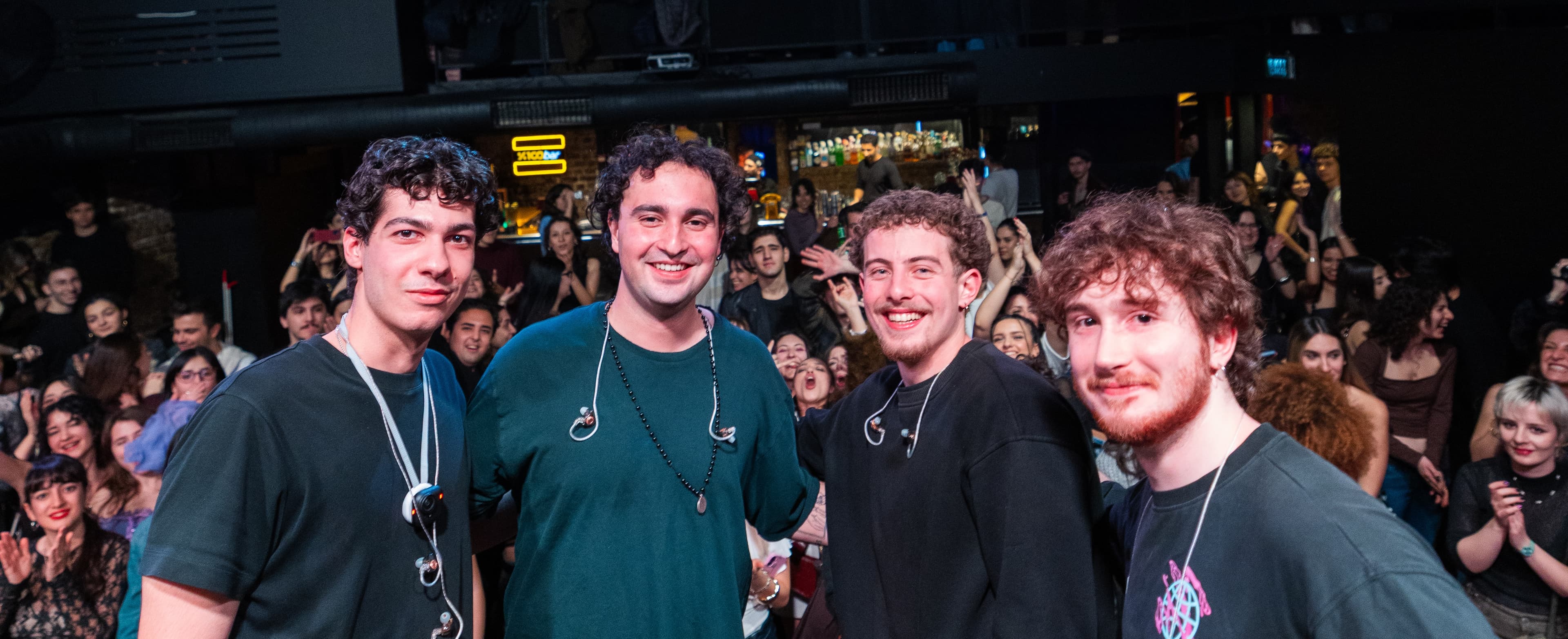 The four members of Maymun Collective posing together in front of a packed crowd after a show.